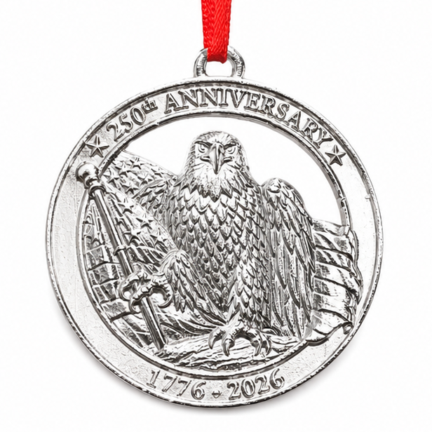 Silver anniversary ornament with eagle design on a wooden shelf with American flags and decor.