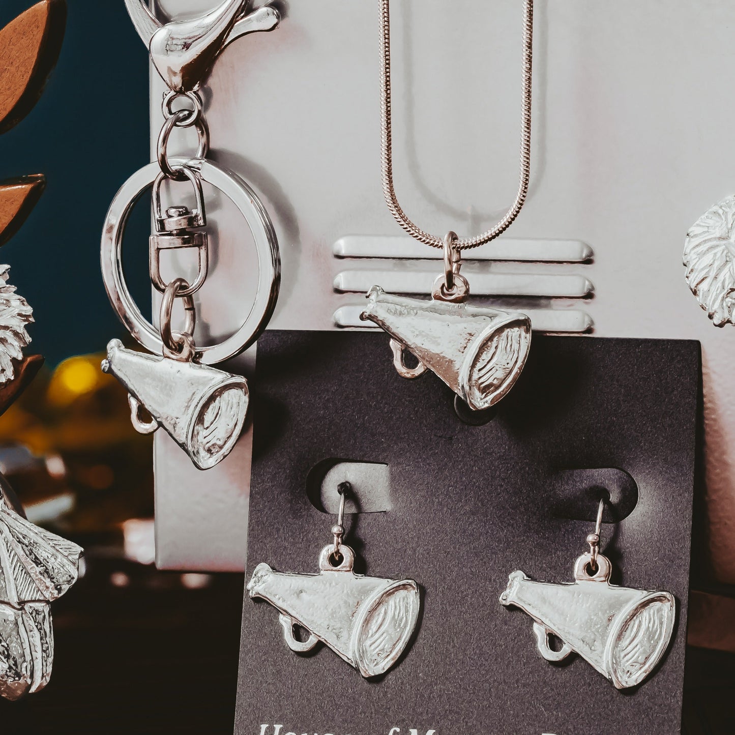 Silver cheerleading-themed jewelry set including keychain, earrings, and pendant on a dark surface with 'House of Morgan Pewter' card.