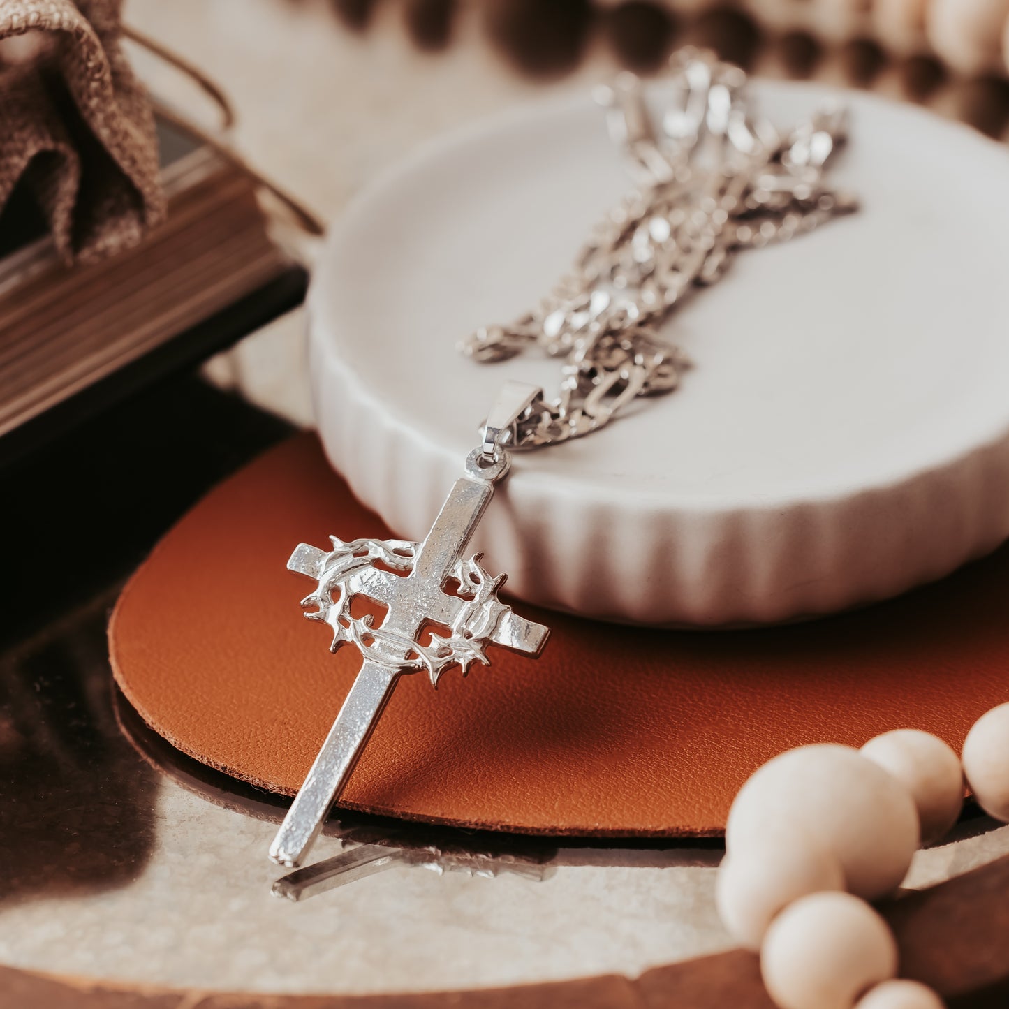 Silver cross necklace with detailed design on a textured surface