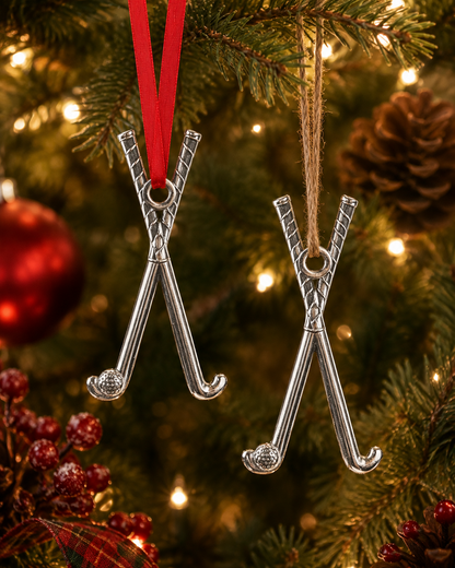 Two silver hockey stick ornaments on a Christmas tree with red ribbon and lights.