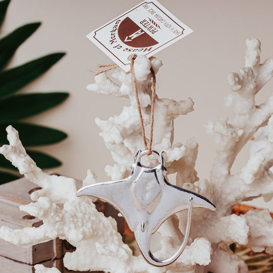 Silver manta ray ornament with a tag on a coral background