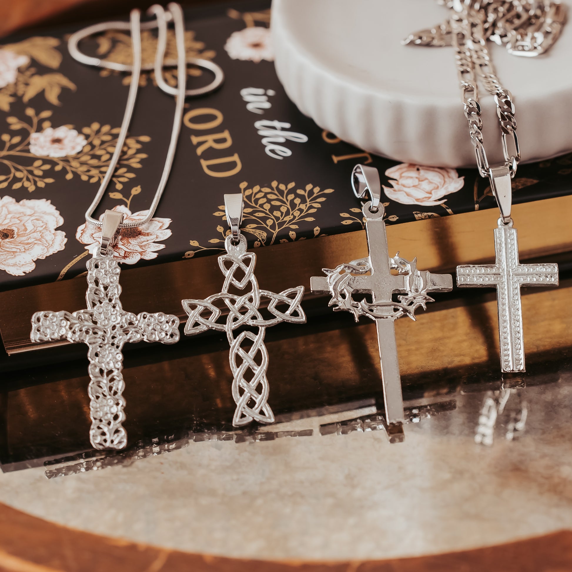 Silver cross pendants on a decorative book with floral designs
